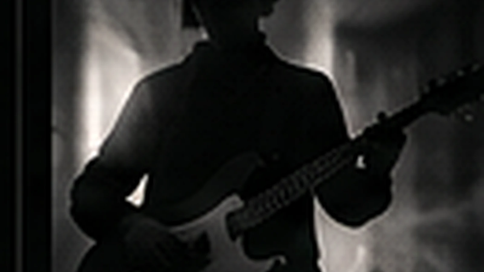 La silueta de un guitarrista contra el humo de un escenario.