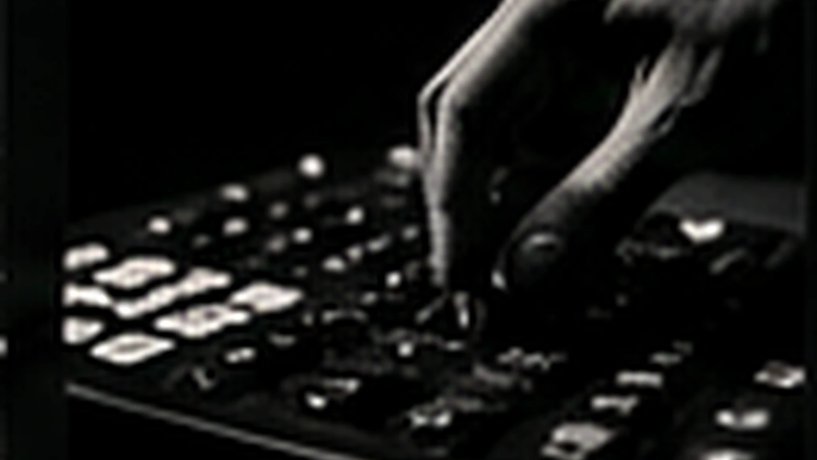 Manos sobre una consola, en la penumbra de un estudio.